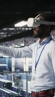 Vertical Data center admin using VR headset to monitor neural network AI systems. Server room employee using virtual reality tech to oversee equipment powering machine learning processes, camera A video