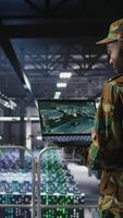 Vertical Military technician reviewing tactical dashboard on laptop screen inside secure server hub. Army expert using strategic communications and infrastructure oversight software on notebook, camera A video