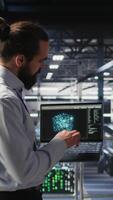 Vertical Military personnel overseeing AI computing operations on laptop in high tech server facility. Army tech experts using artificial intelligence to oversee communication systems, camera A video