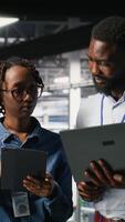 Vertical Data center admins running diagnostics on equipment using system monitoring tools to identify errors, doing brainstorming. IT experts work together to prevent failure and minimize downtime, camera B video