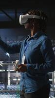Vertical Data center admin wearing VR headset using artificial intelligence neural networks technology. Server hub developer using AI programming language and virtual reality to update hardware, camera A video