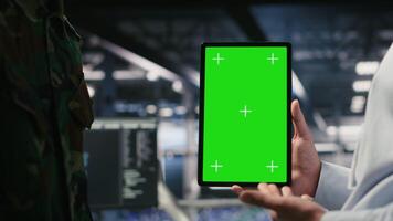 Military technicians in data center use green screen mockup tablet to monitor systems. Army operators in server room ensuring stable infrastructure using chroma key device, camera B video
