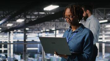 Portrait of joyful computer scientist in data center monitoring neural network LLM visualization. Upbeat woman in server farm overseeing rigs powering machine learning processes, camera B video