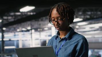 System administrators on data center industrial platform analyzing performance outputs on laptop. Server hub teamworking colleagues finetuning server rig configurations using notebook, camera B video