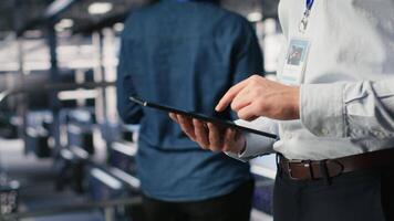 Close up of server room worker checking code on tablet next to colleague reviewing AI LLM visualization. Data center IT expert using device to monitor artificial intelligence systems, camera B video