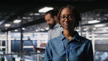 Happy technician next to server hub engineering team colleagues reviews AI diagnostics. Cheerful african american woman working in data center to maintain operational reliability, camera B video