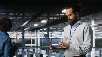Server farm IT expert managing storage arrays supporting machine learning training workflows. Technician on industrial platform doing maintenance on rigs handling AI processing tasks, camera B video