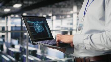 Close up of IT specialist in server room doing AI deep learning automatization. Data center software developer using notebook, doing hardware maintenance using AI, camera B video