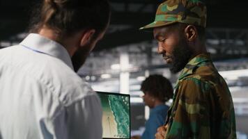 Military IT specialists in server hub using laptop scanner tools to oversee battlefield during warfare. Army data center admins doing transmission analysis and live UAV system monitoring, camera B video