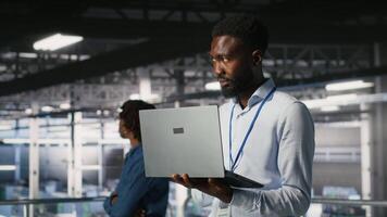 Server hub IT professional managing storage arrays supporting deep learning training workflows. Engineer on industrial platform performing maintenance on servers handling AI processing tasks, camera B video