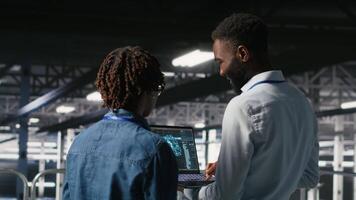 Data center engineering team doing maintenance on rigs handling AI processing tasks. Server hub teamworking colleagues managing storage arrays supporting deep learning training workflows, camera B video