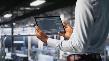 Data center admin checking code on tablet next to colleague reviewing AI visualizations in blurry background. IT experts use device to analyze neural networks outputs, ensuring stable gear operations video