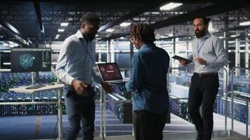 Worried workers trying to fix hacked infrastructure systems. Panicked engineers in data center react to ransomware warning on laptop screen, scrambling to launch emergency response protocol, camera A video