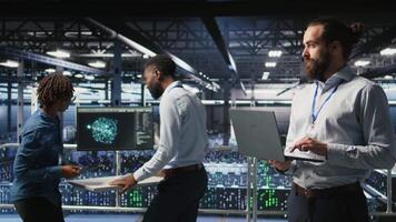Computer scientists on data center industrial platform analyzing performance outputs on laptop. Server farm IT experts collaborating on finetuning rigs configurations, camera A video