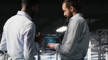 Data center team leader and worker reviewing performance dashboards of AI equipment rigs. Server room supervisor oversees programmer examining machine learning algorithms on screen, camera B video
