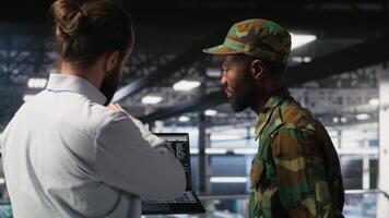 Military units overseeing AI computing operations on notebook in high tech server facility. Army tech experts using machine learning intelligence to oversee communication systems video
