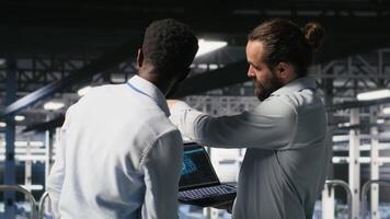Data center workers cooperating, doing maintenance on rigs handling AI processing tasks. Server hub admins doing brainstorming, managing storage arrays supporting deep learning technology, camera B video