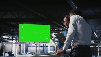 Data center colleagues working on green screen PC, updating storage infrastructure. IT engineering team using mockup computer in server hub workspace filled with networking tech, camera A video