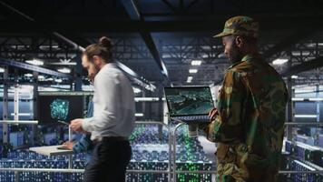 Soldier in server room uses geospatial data to support evacuation during emergency operations. Military data center personnel in uniform coordinating disaster response logistics using laptop, camera A video