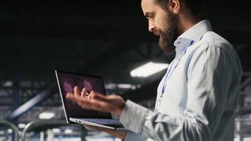 Annoyed engineer in data center reacting to critical error message on laptop. Irked IT professional attempts to resolve system fault impacting backend infrastructure performance, camera B video