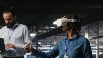 Engineer on data center industrial platform analyzing performance outputs using virtual reality tech. Server hub colleagues finetuning server rig configurations using VR headset tech, camera B video
