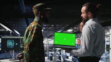 Military command center engineering team using chroma key notebook. Army IT expert and coworkers in data center using green screen laptop to defend networks against threats, camera A video