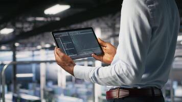 Close up of data center programmer looking at code debugging tools running on tablet. Server farm IT professional checking machine learning script automating tasks, camera B video