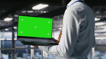 Close up of engineer on data center industrial platform analyzing performance outputs on green screen laptop. Server room IT expert finetuning server rig configurations using mockup notebook, camera B video