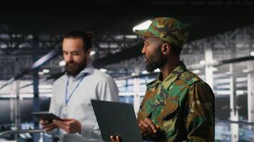 Army technician in command center server room using laptop to install and maintain IT systems. Military data center admin overseeing computer networks and information systems, camera B video