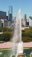 Buckingham Fountain with Chicago skyline on sunny day. View of Buckingham Fountain in Grant Park with water jets creating a rainbow effect, set against the video