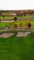 Scenic Golf Course with Autumn Trees, Aerial view of a lush golf course featuring sand traps, vibrant autumn trees, ponds, and green fairways under soft video