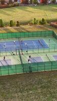 Aerial View of Pickleball Courts in Use, Drone shot of outdoor pickleball courts with players engaged in games, surrounded by green fencing and open fields. video