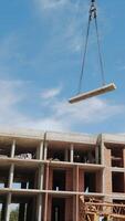 Construction Site with Crane Lifting Concrete Slab. A dynamic view of a construction site where a crane is lifting a concrete slab towards the upper levels of a video