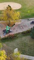Aerial View of Community Playground and Park. Aerial shot of a vibrant community park featuring a playground, swings, walking paths, sports fields, and lush video