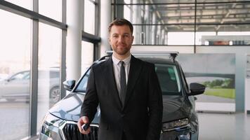 Car salesman showing key and thumb up in dealership video