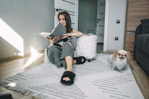woman enjoying a peaceful reading session with her japanese chin dogs in sunlit living room, highlighting a quiet moment at home photo