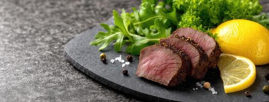 A piece of meat with lemon and herbs on a black plate photo