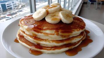 A stack of pancakes topped with bananas and syrup photo