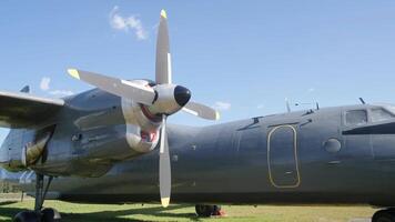 Visitors explore a classic military aircraft on display under bright sunshine, admiring its unique design and powerful propellers in a lively outdoor setting. video