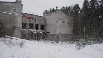 An eerie and haunting view of a dilapidated, abandoned structure surrounded by towering, snowcovered trees video