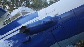 Detailed look at the blue vintage aircraft highlighting the propeller, cockpit, and engine features surrounded by trees under clear skies. video