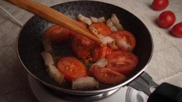 Fresh tomatoes and meat are being sauteed together in a skillet, combining flavors and aromas for a delicious and hearty meal preparation. video