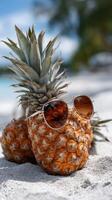 Pineapple with sunglasses on the beach photo