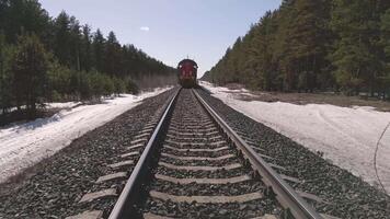Train travels along snowy railway in forest during bright day video