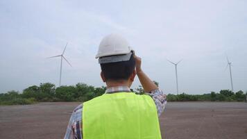 Rare shot of engineer overseeing windmill site operations from distance at renewable energy facility on overcast day video