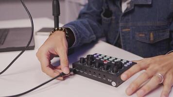 Close-up of hands adjusting podcast audio interface during setup video