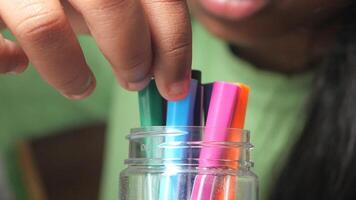 Organizing colorful markers in a jar during creative time video