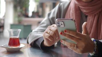 Enjoying tea while browsing on a smartphone in a cafe video
