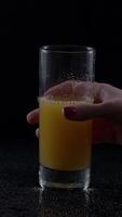 Woman's hand reaching for a refreshing glass of orange juice in a dimly lit setting with condensation on the glass video