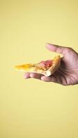 Hand with a colorful pizza slice on yellow bg video